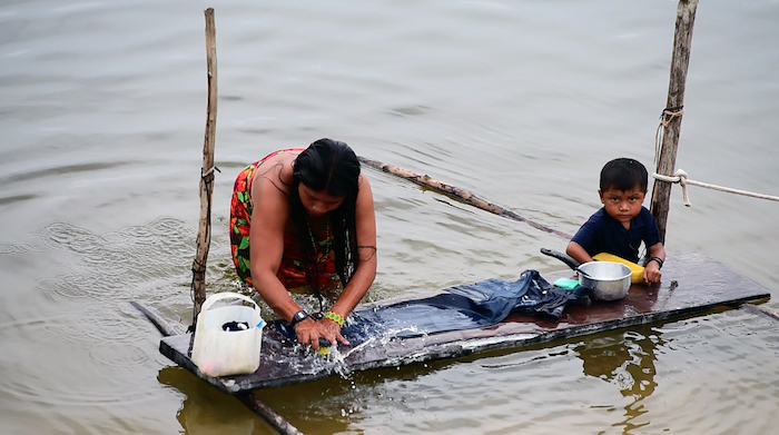 An indigenous woman washing clothes in the Teles Pires River. The Munduruku and other indigenous groups rely on the river for everything — for work and play, as livelihood and a transportation corridor. The Teles Pires dam has negatively impacted many of these activities. Photo: Thais Borges
