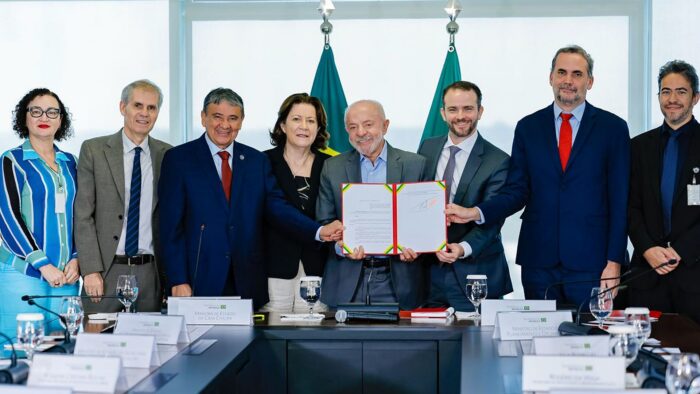 President Lula stands with government officials holding an open document during a Bolsa Família announcement at the Palácio do Planalto in Brasília.