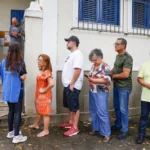 Voters queue beside the entrance to Escola Municipal Barão Homem de Mello in Rio de Janeiro, while an election worker directs people into the building.