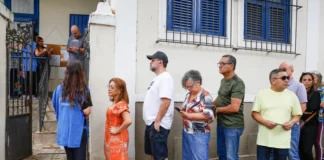 Voters queue beside the entrance to Escola Municipal Barão Homem de Mello in Rio de Janeiro, while an election worker directs people into the building.