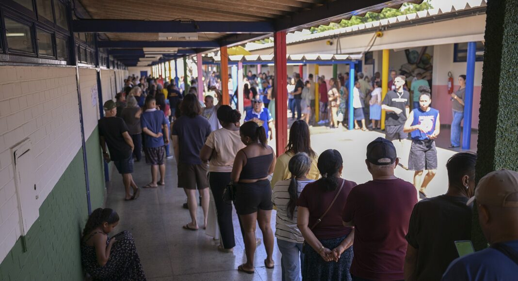 Voters wait in a long queue along a covered corridor at a polling station in Gama, Federal District, Brazil, during the first round of the 2026 elections.