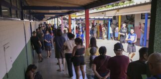 Voters wait in a long queue along a covered corridor at a polling station in Gama, Federal District, Brazil, during the first round of the 2026 elections.