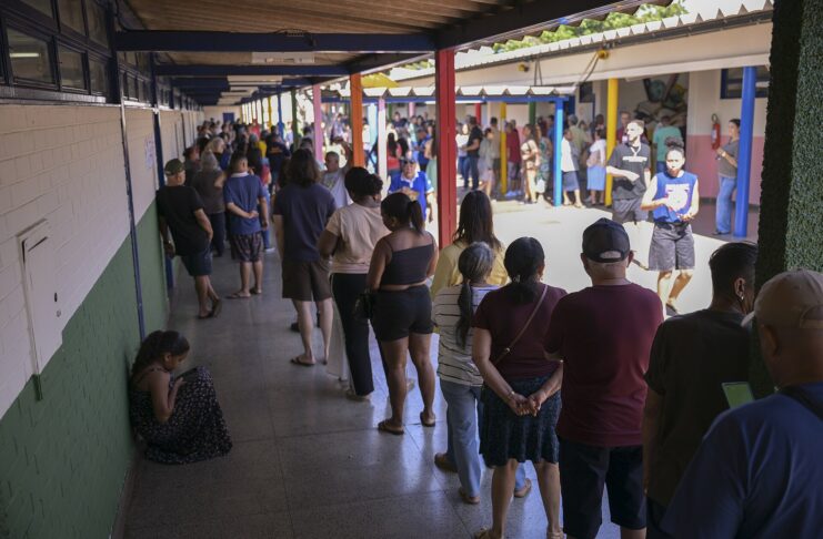 Voters wait in a long queue along a covered corridor at a polling station in Gama, Federal District, Brazil, during the first round of the 2026 elections.