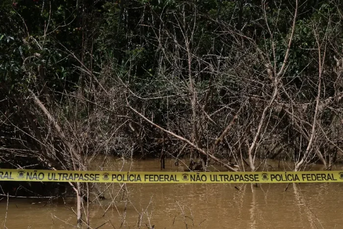 Yellow Brazilian Federal Police tape marked ‘Do not cross’ stretches across flooded woodland.